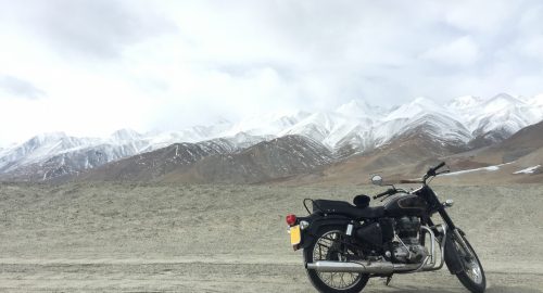 Motorcycle alone enduro traveler with suitcases standing on rocky plateau in cloudy weather on the background of endless mountain steppe Plateau Ukok Altai mountains Siberia Russia.